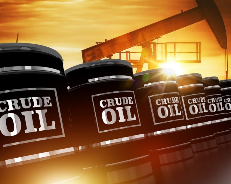 Crude oil barrels with pump jack at sunset representing oil production and trading