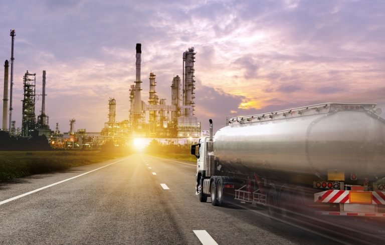 Fuel tanker truck transporting base oil toward refinery at sunset
