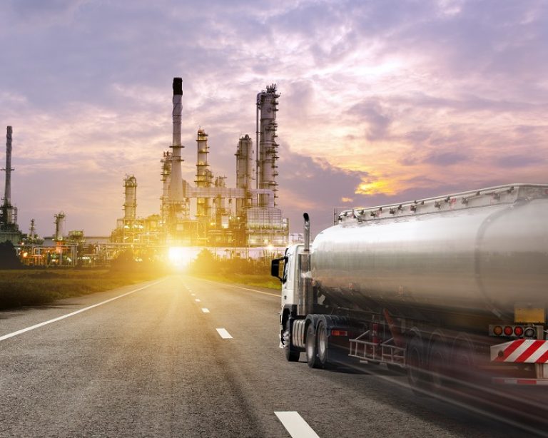 Fuel tanker truck transporting base oil toward refinery at sunset
