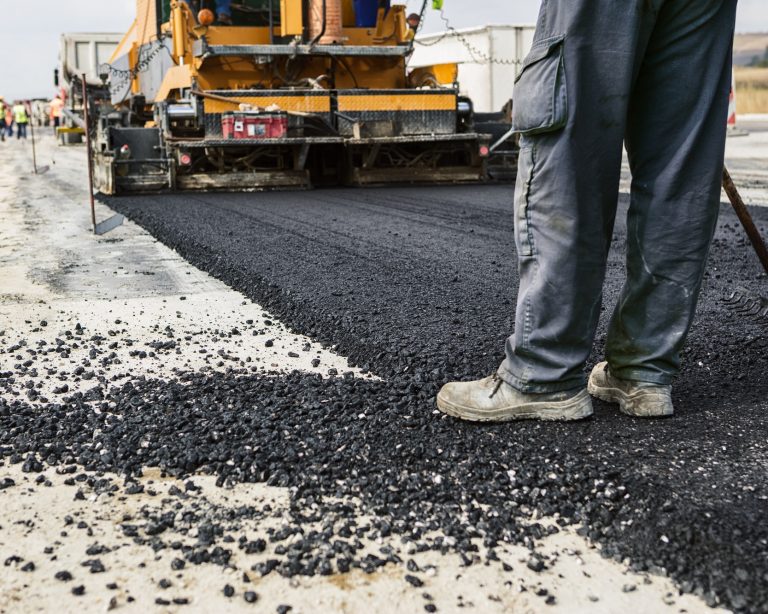 Road construction crew laying hot asphalt bitumen with paving machine